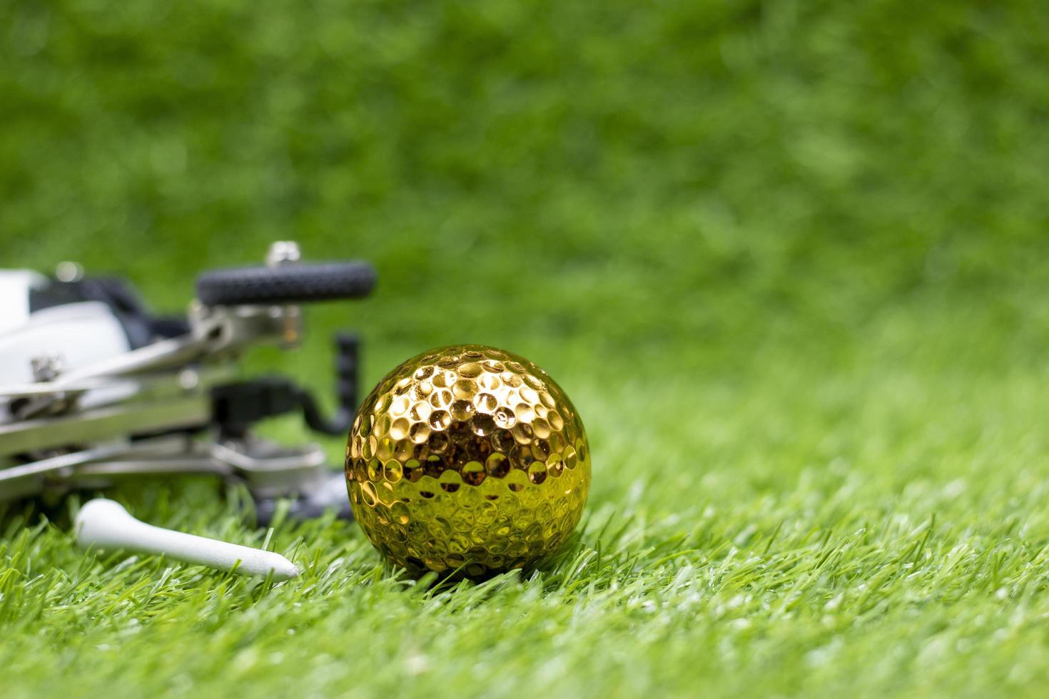 Golden golf ball is on green grass photo
