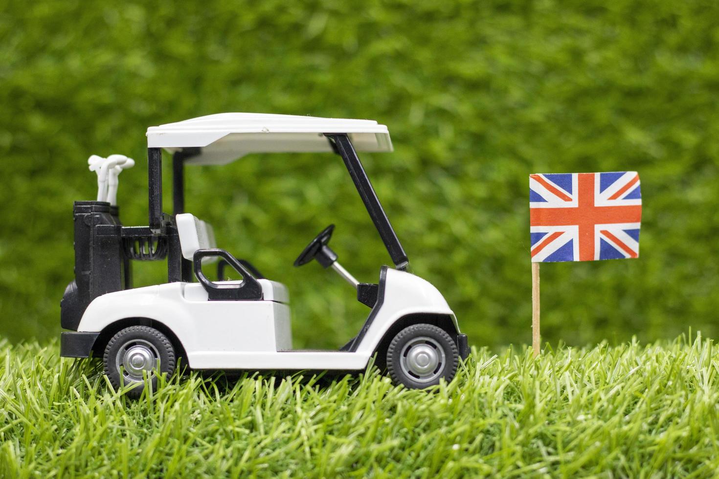 Golf cart with Union Jack Flag are on green grass background photo