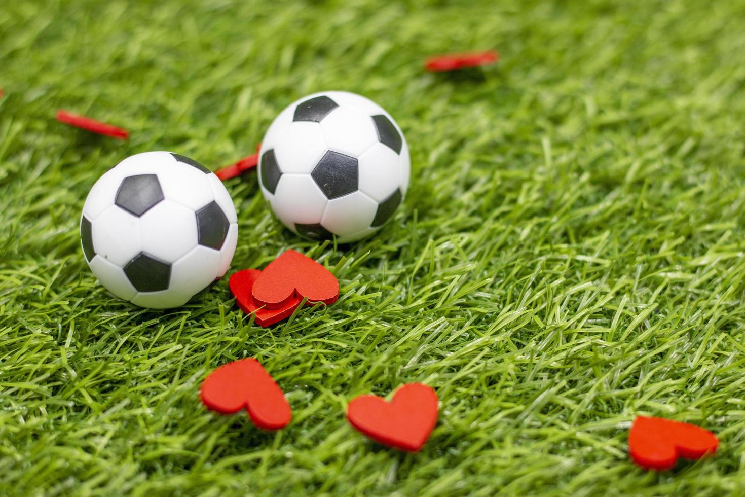 Balón de fútbol con corazón rojo sobre hierba verde foto