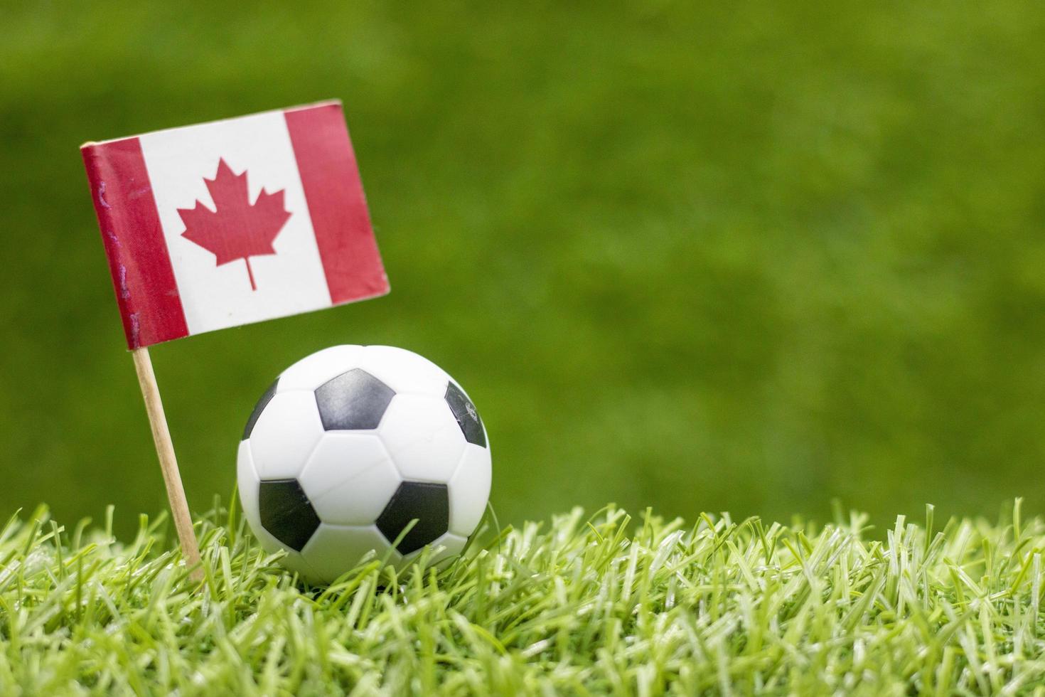 Balón de fútbol con la bandera de Canadá sobre fondo de hierba verde foto