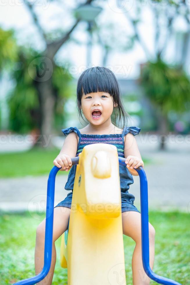 niña asiática disfruta jugando en un parque infantil foto