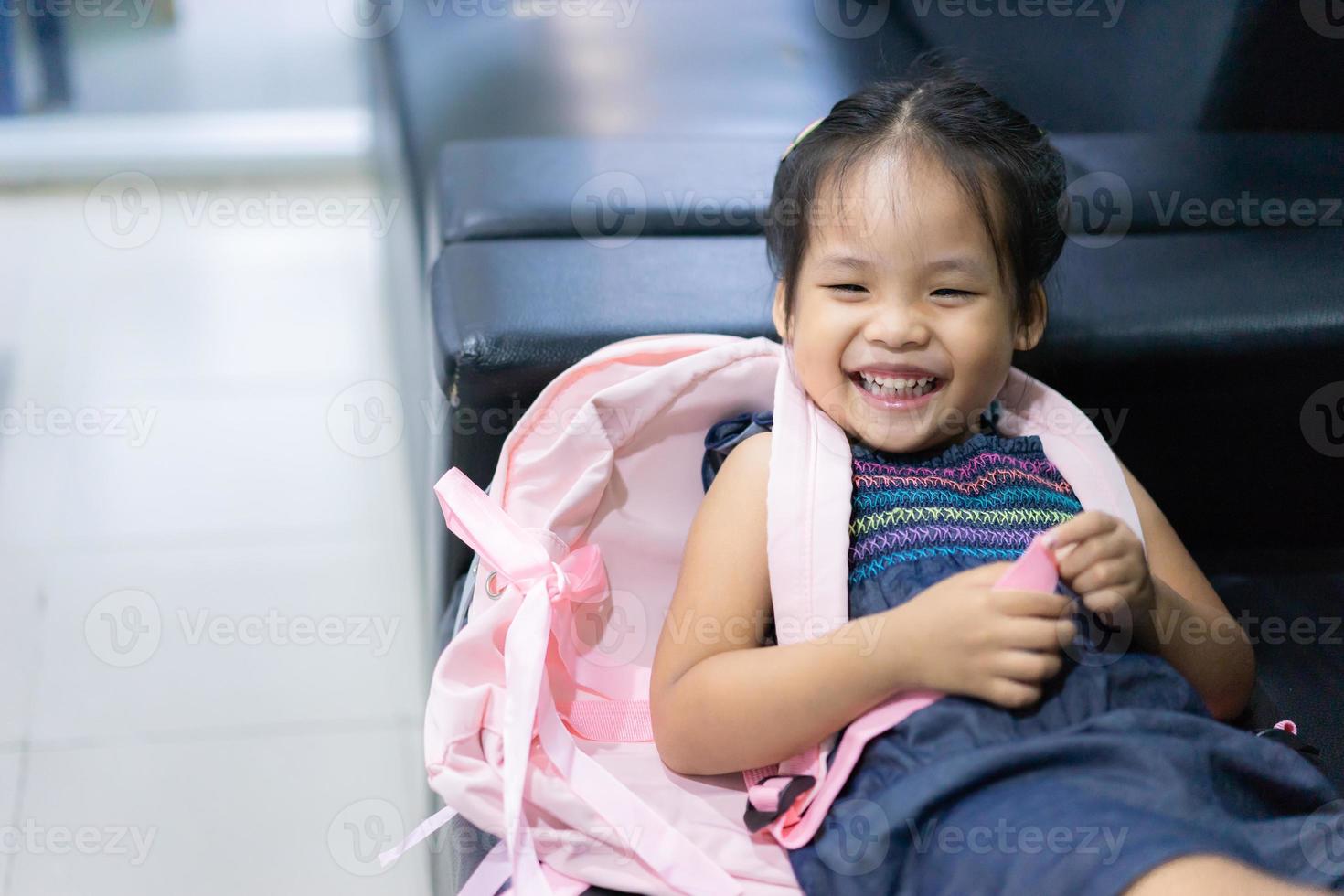 Niña asiática con mochila acostado en el sofá listo para volver a la escuela foto