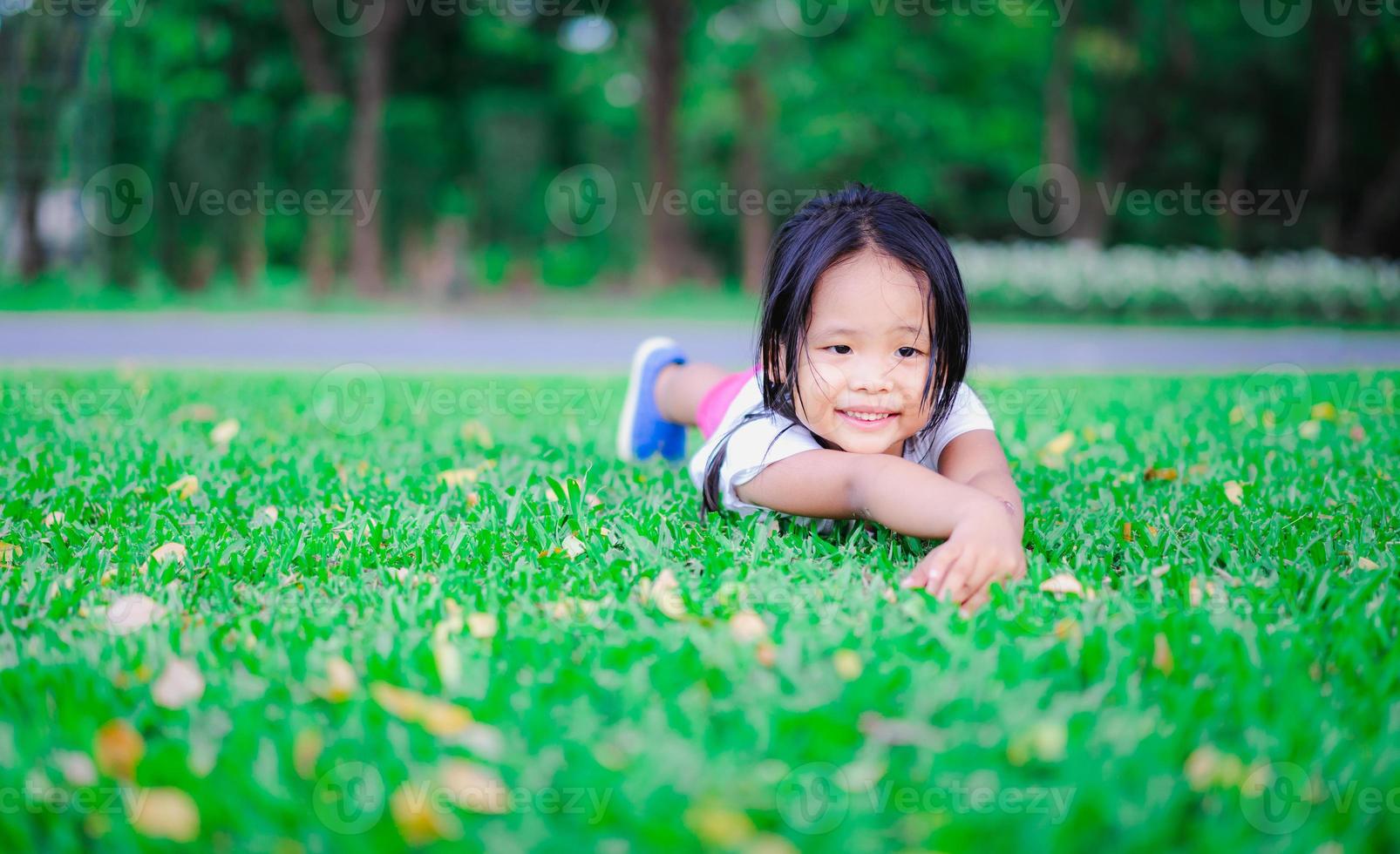 niña asiática tirada en el suelo y mirando algo foto