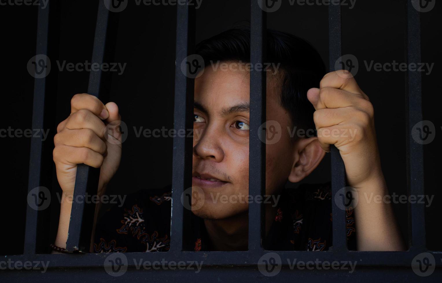 expresión de hombre sujetando rejas en la cárcel foto