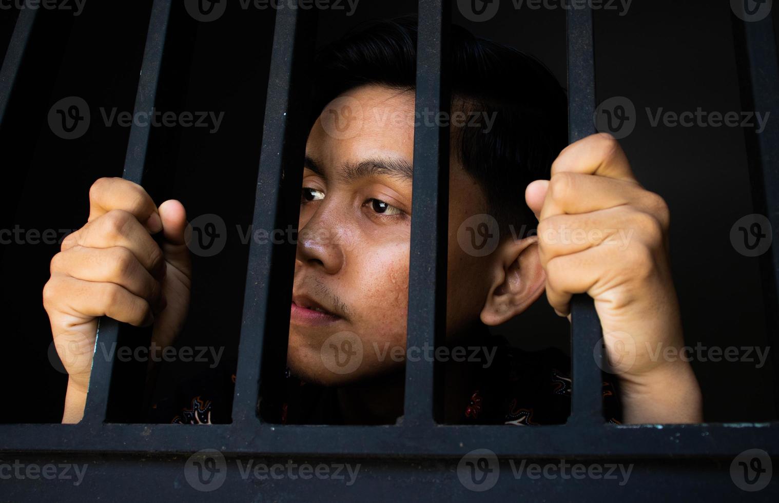 expression of man holding bars in prison photo