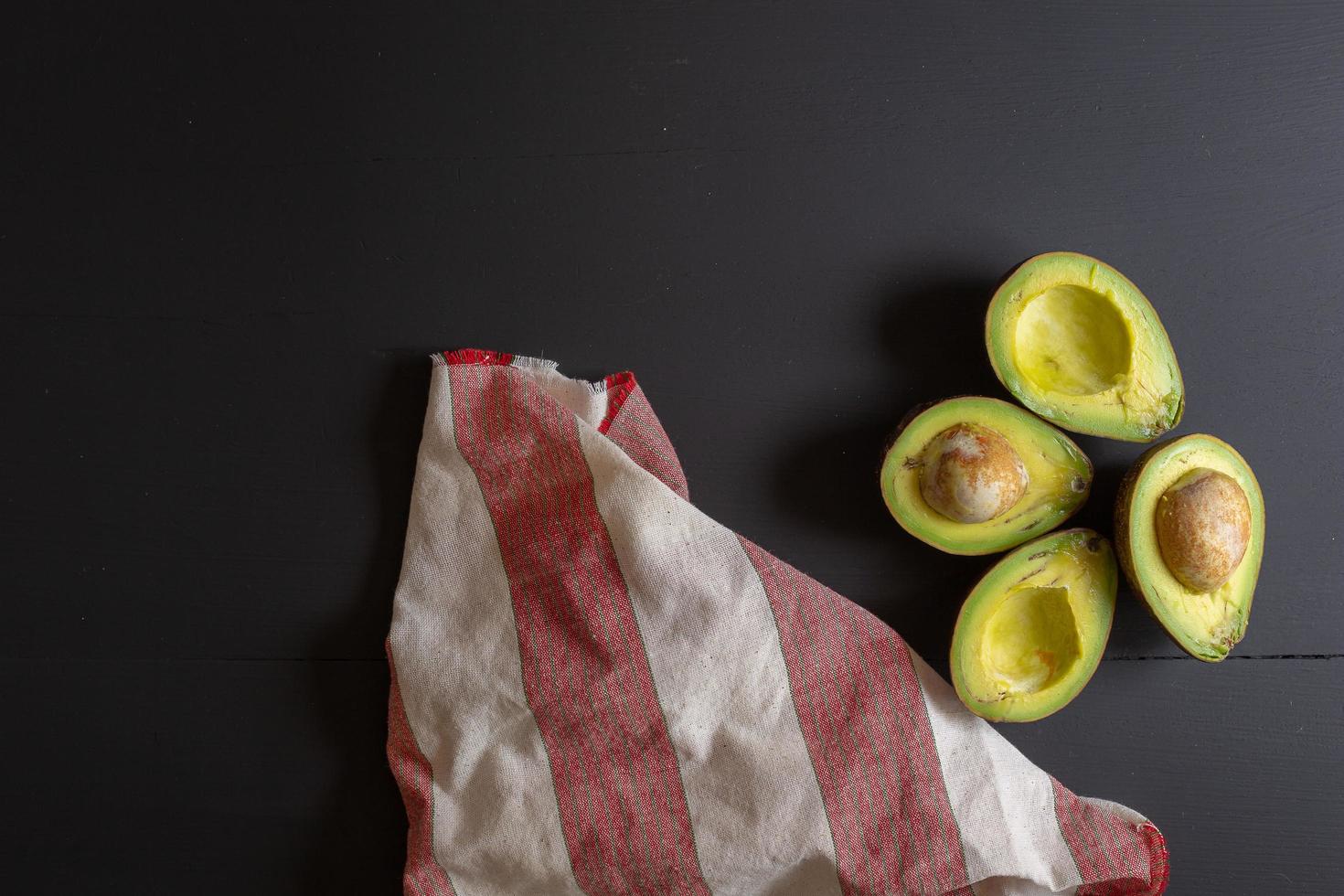 Fresh organic avocado sliced in half on black wooden table photo