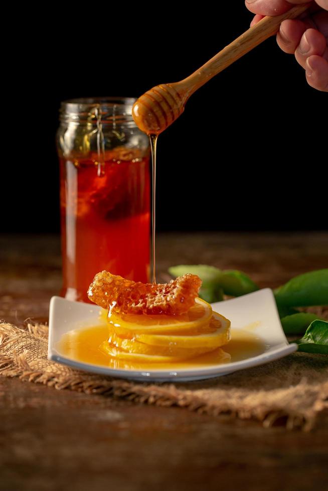 jugo de limón con miel en la mesa de madera, limones y hojas de salvia foto