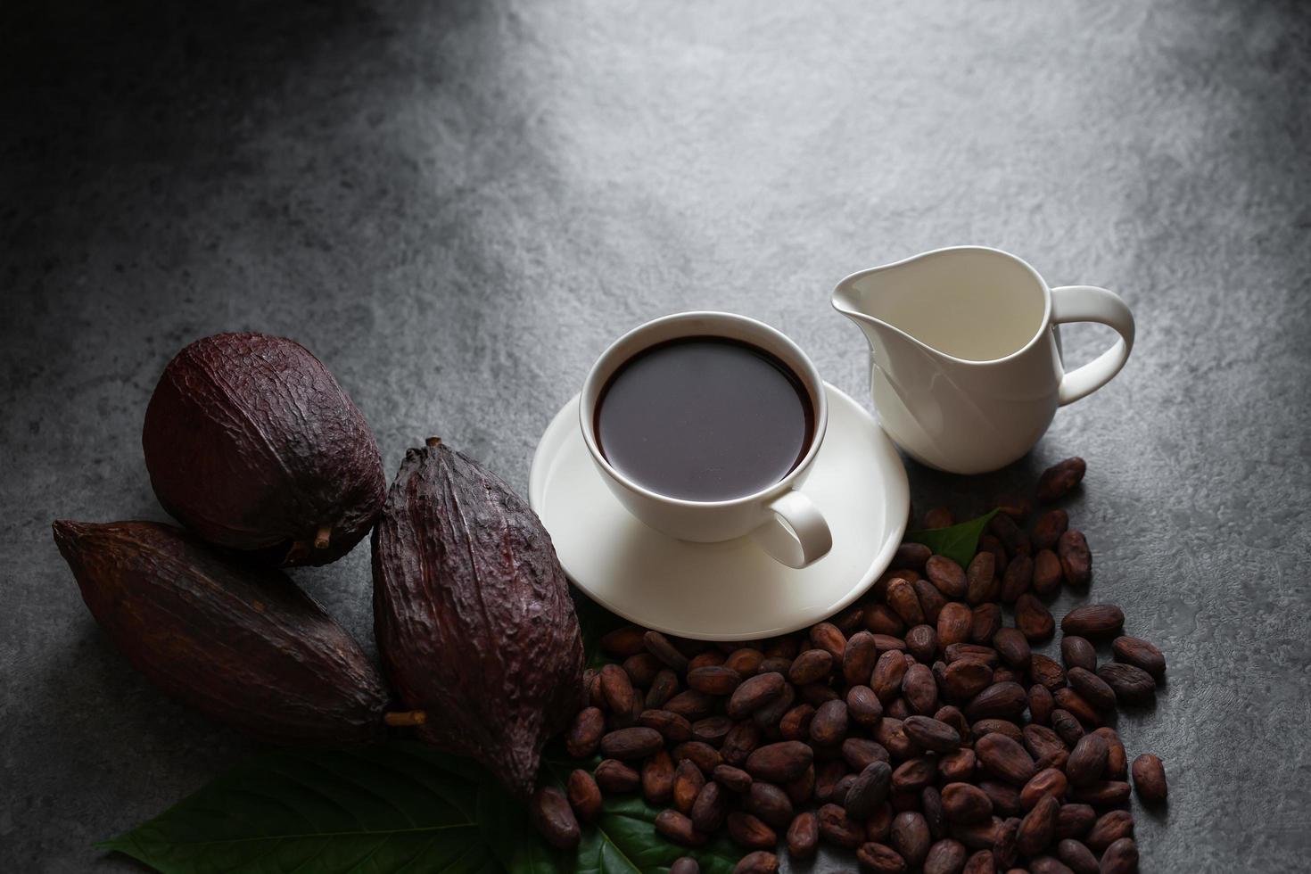 Hot chocolate and Cocoa pod cut exposing cocoa seeds on dark table, top view with copy space photo