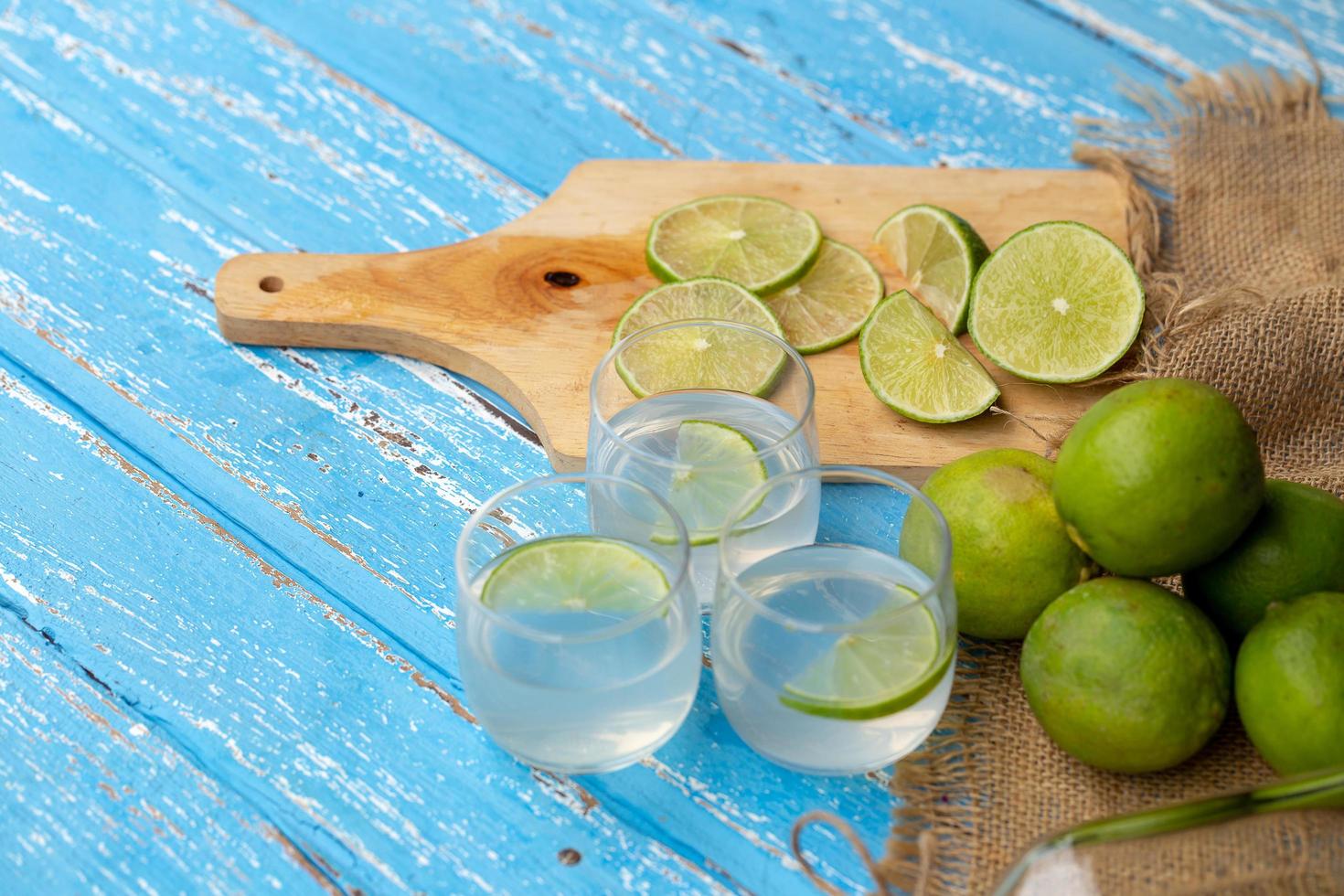 Lime juice and lemon on a blue wooden table photo
