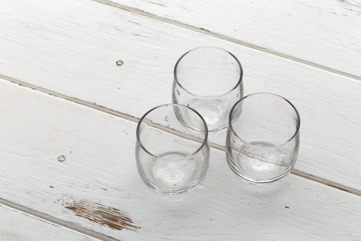 Tres vasos vacíos en una mesa de madera blanca foto