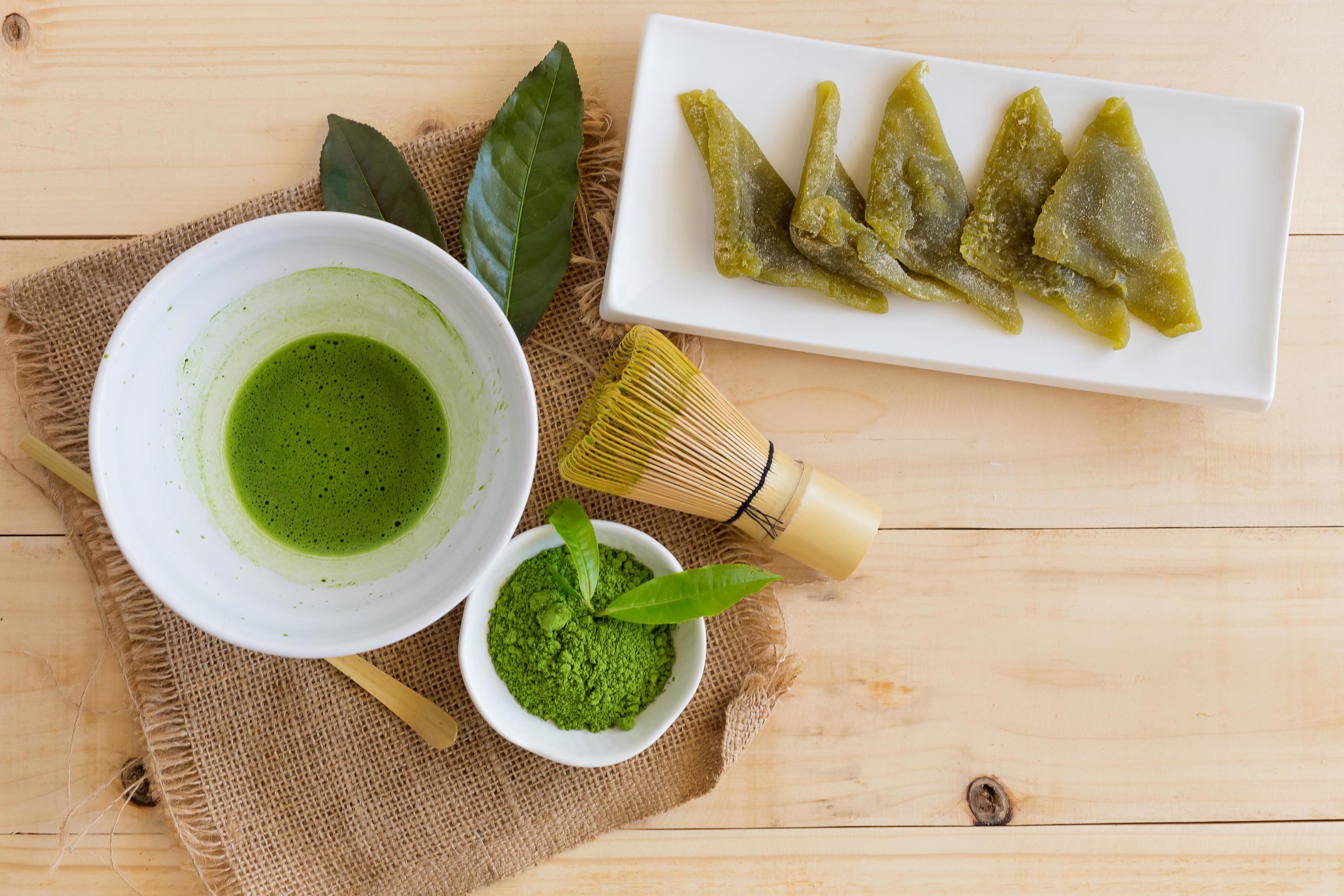 Complete matcha tea ceremony setup with organic green matcha powder, traditional bamboo whisk, wooden spoon and ceremonial bowl