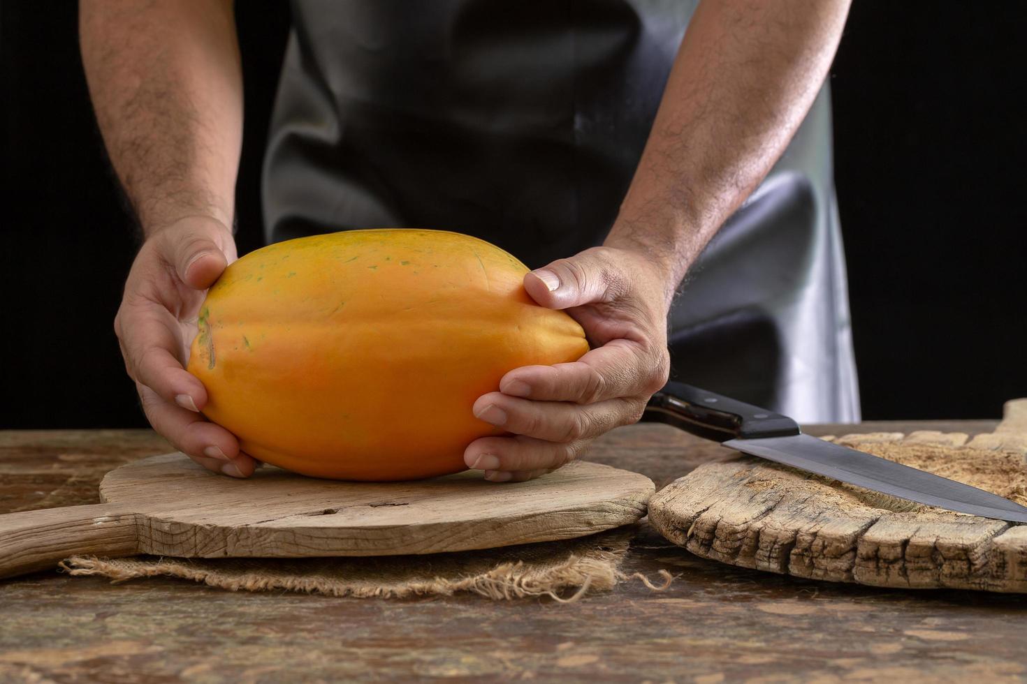 Papaya madura en manos de hombres sobre fondo de madera foto