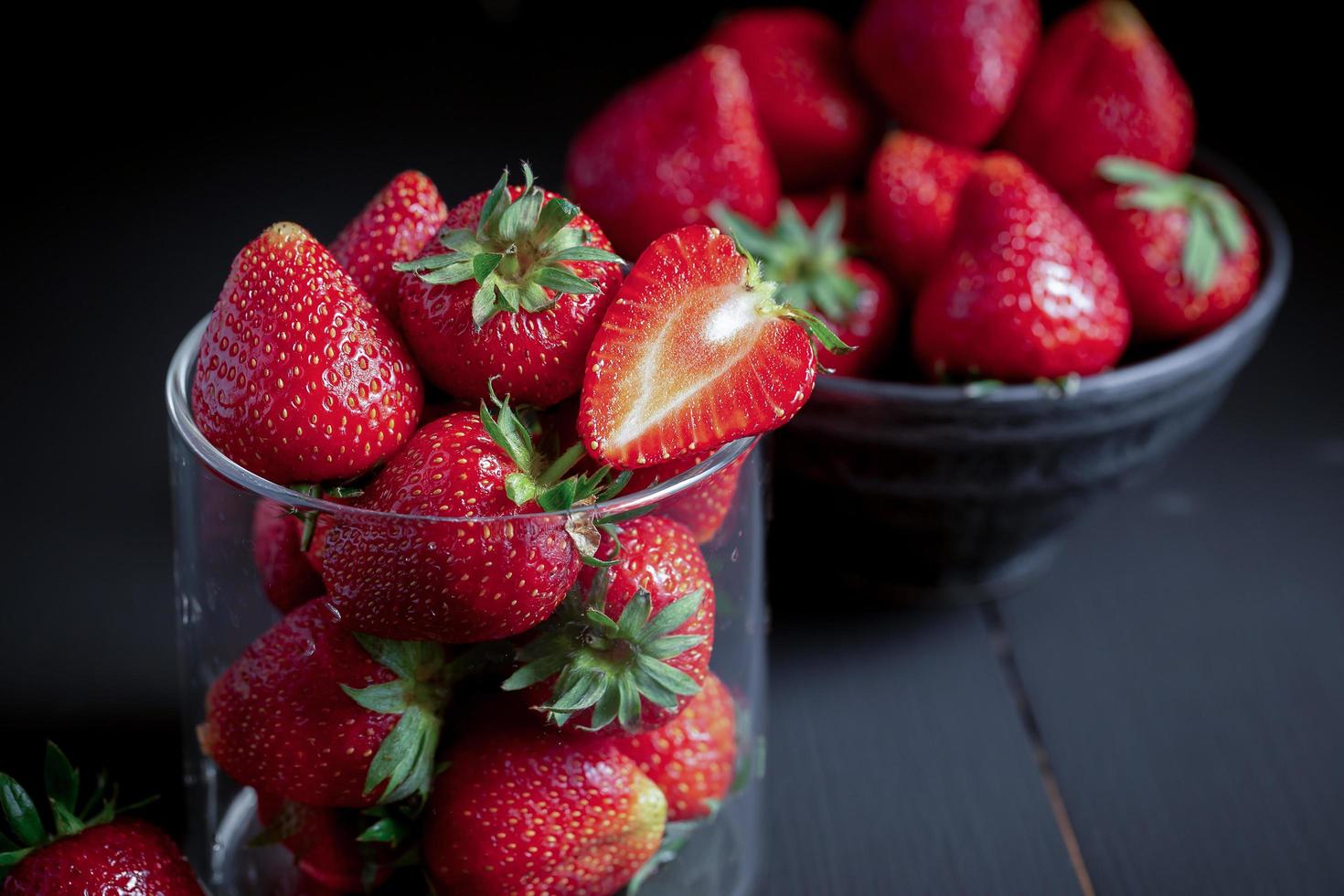 Fresas rojas maduras sobre mesa de madera negra foto