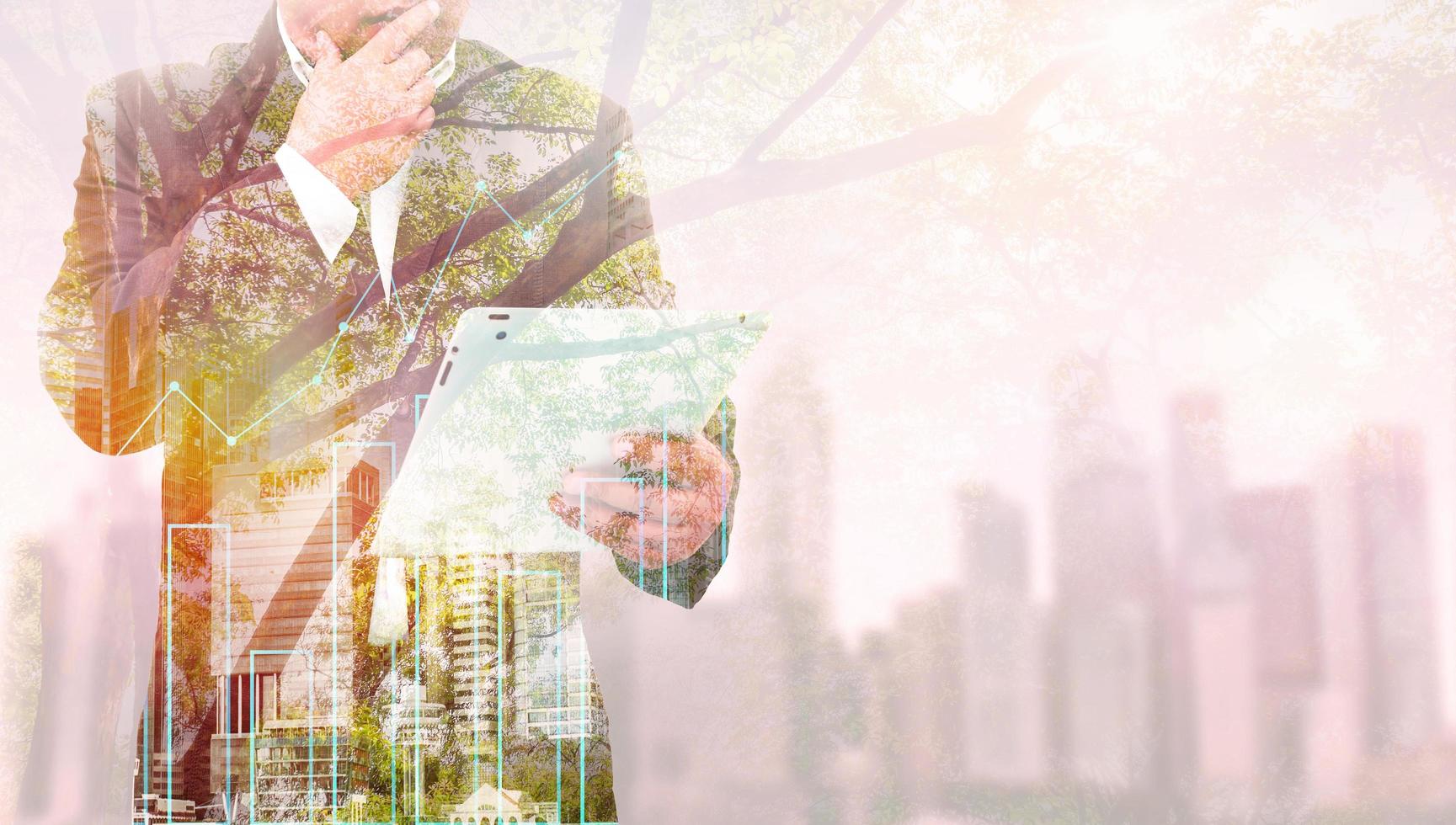 Double exposure of success businessman using tablet with city landscape background. Nature and Building construction. Mixed media photo