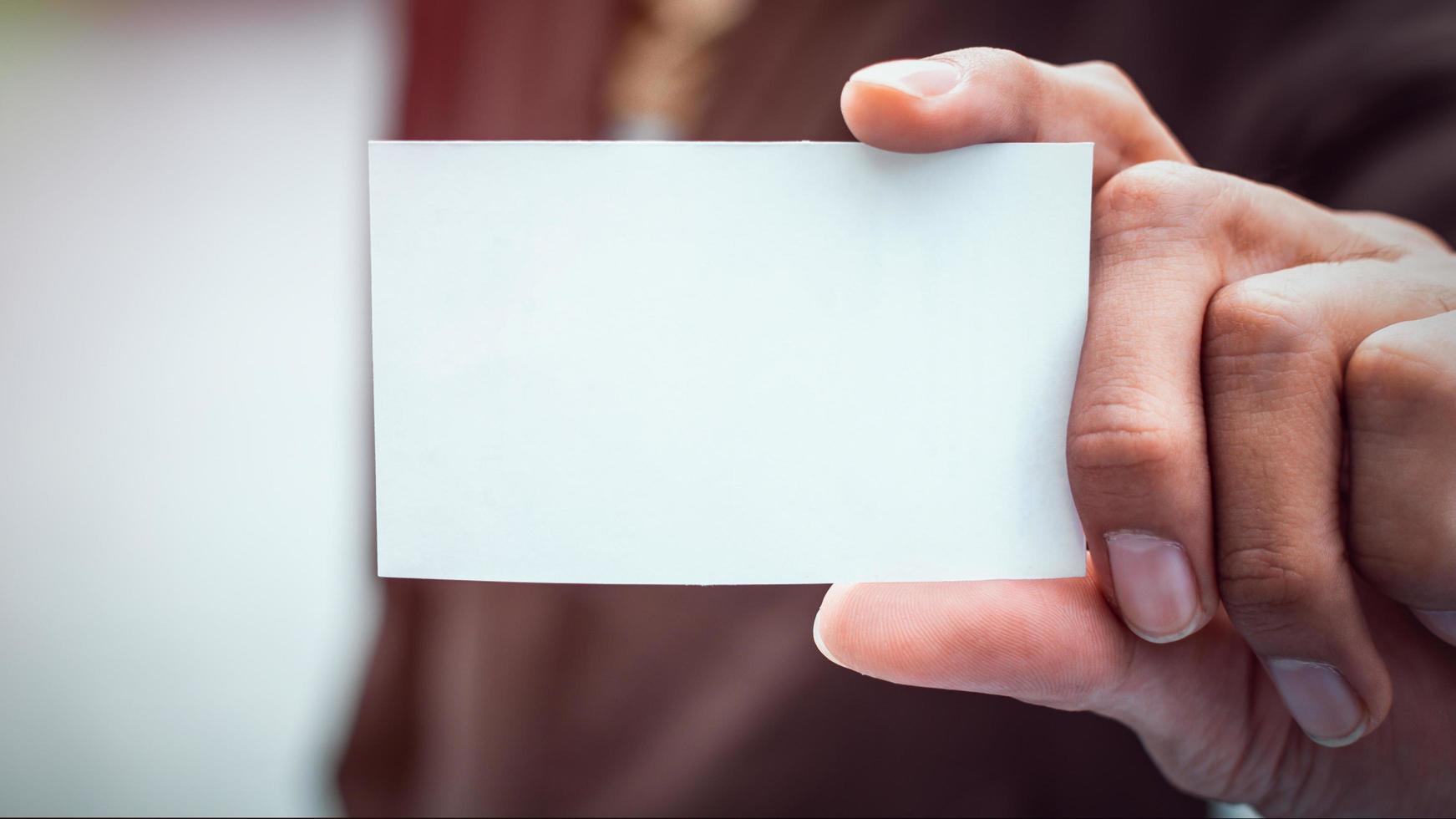 Businessman holding white business card. Mockup bank paper for ads and text. photo