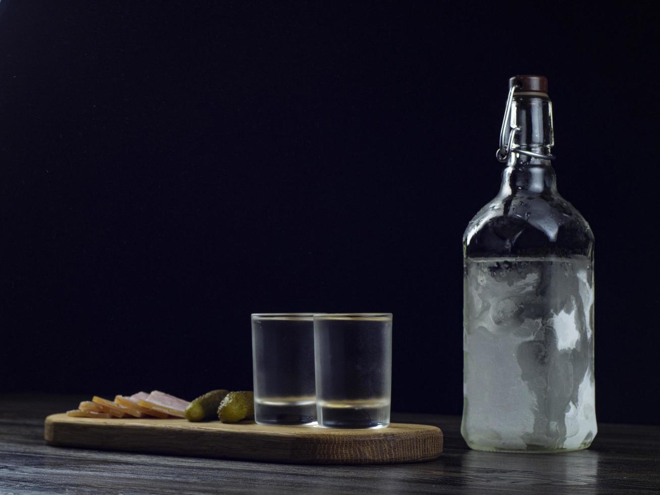 botella de vodka, dos vasos empañados con vodka frío foto