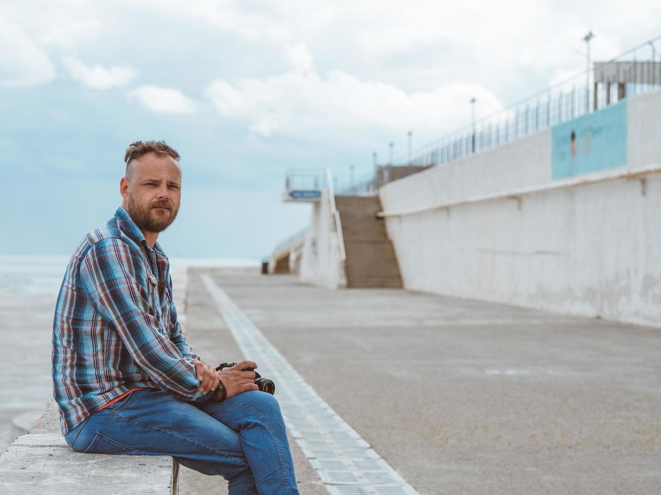 bearded man with mohawk sits on a concrete bench photo
