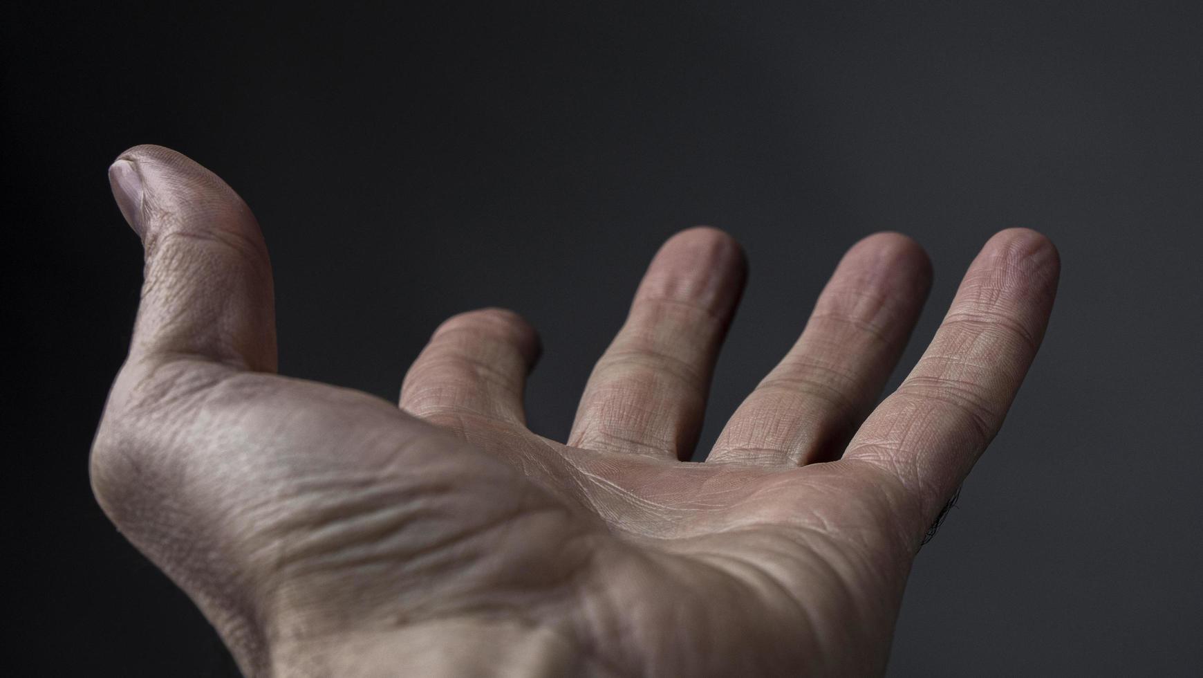 La mano del hombre pide algo sobre un fondo oscuro foto