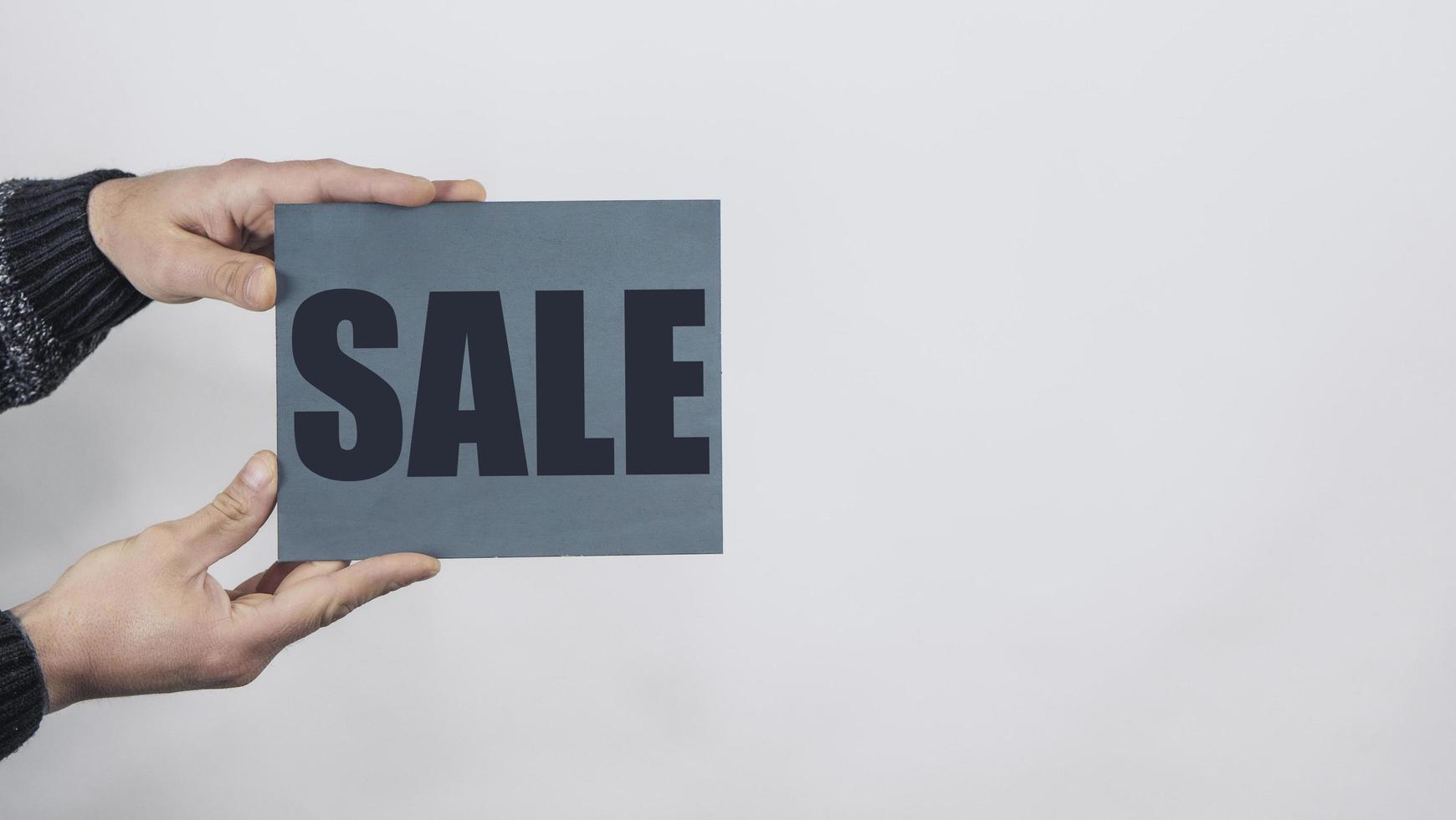 Man Hands Holding A Sign Saying Sale photo