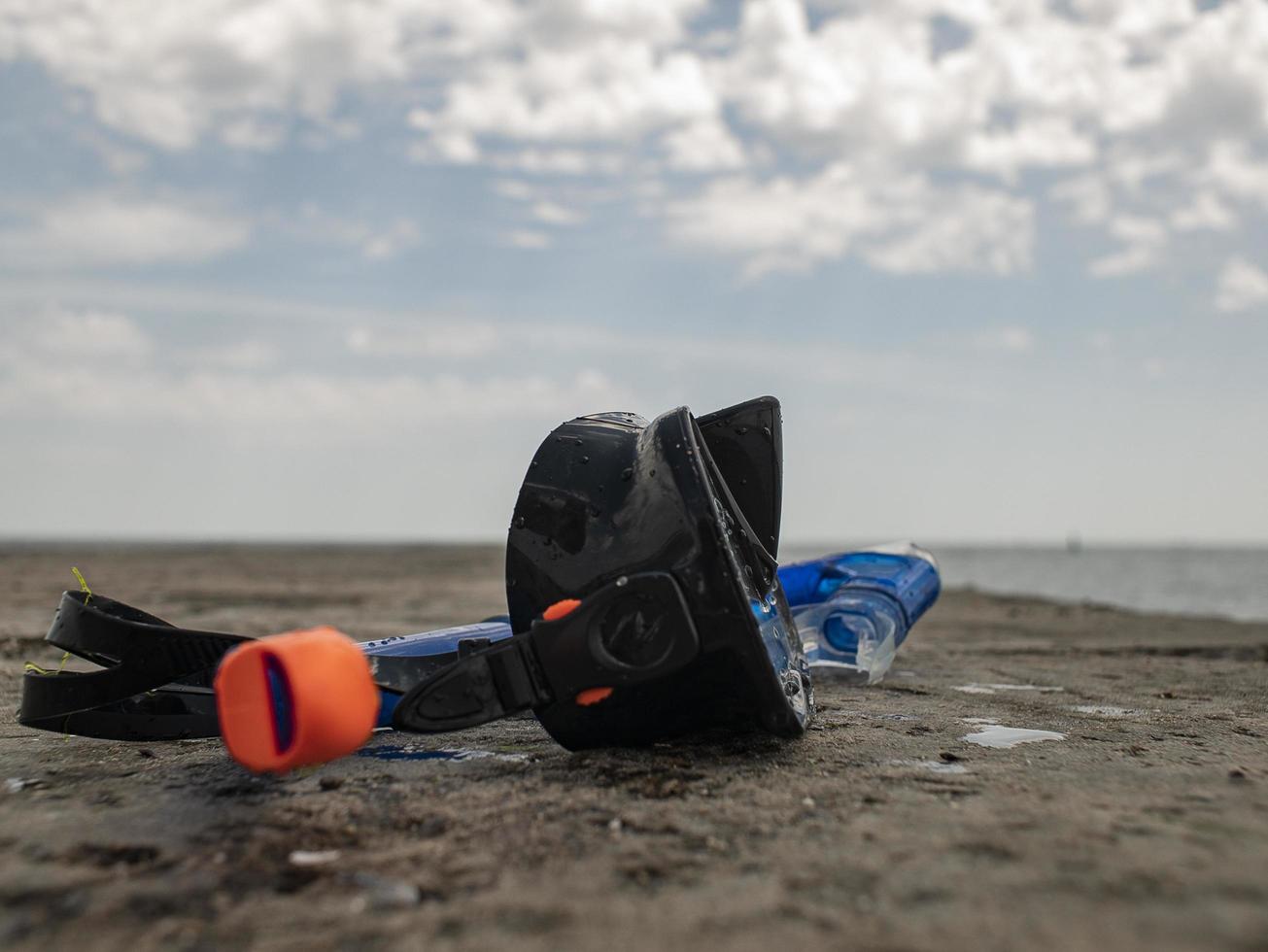 black diving mask and snorkel on a concrete pier against the background of blue sky and clouds photo