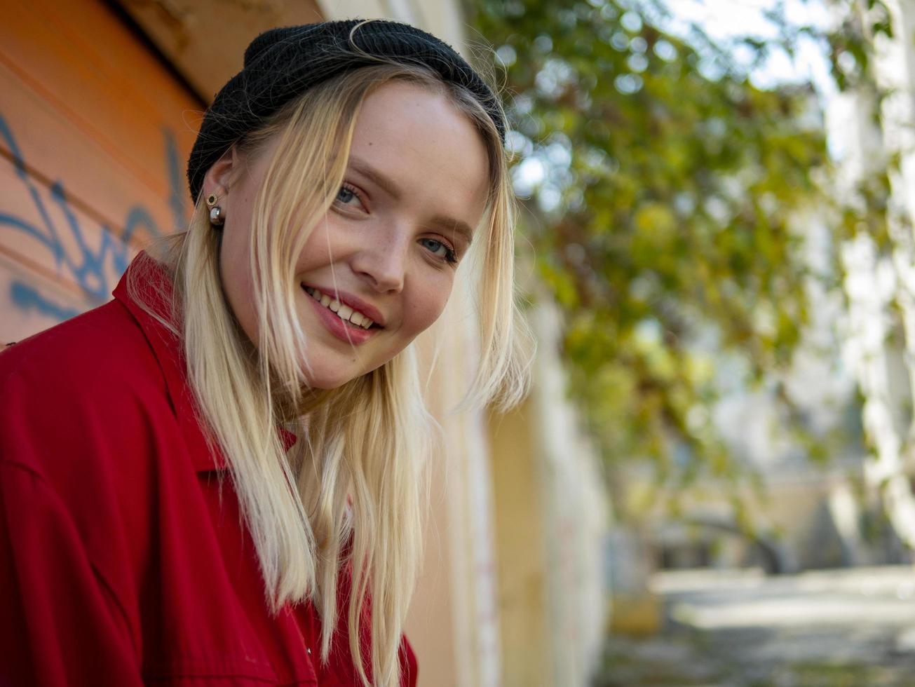 portrait of smiling young cute girl in knitted hat outdoors standing near the wall photo