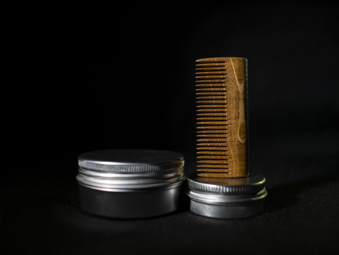 Wooden comb and jars of beard and mustache wax on a black background photo