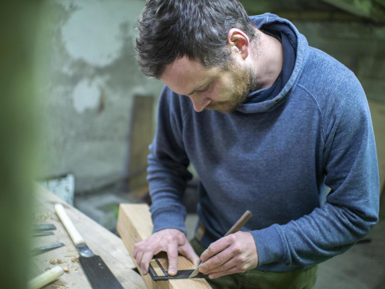 un carpintero con barba marca el cuadrado de la viga de madera foto