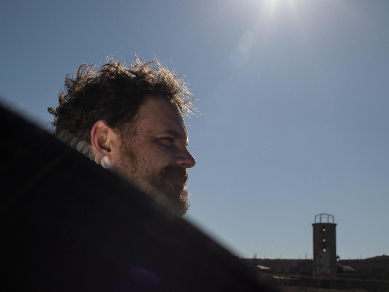 portrait of a man with a beard and mustache holding a reflector in front of the sun photo