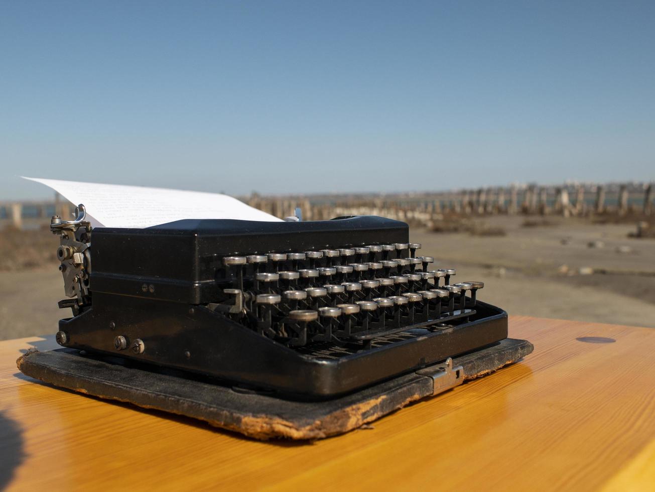 Máquina de escribir vintage sobre una mesa de madera, hecha a mano sobre un fondo de cielo azul foto