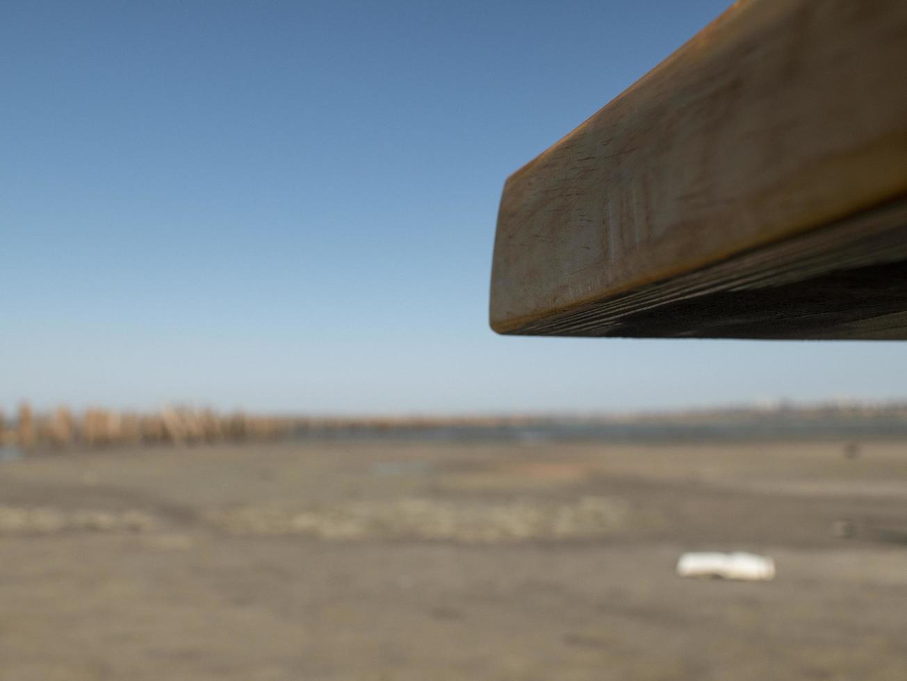 handmade wooden coffee table corner on blue sky and sand background photo