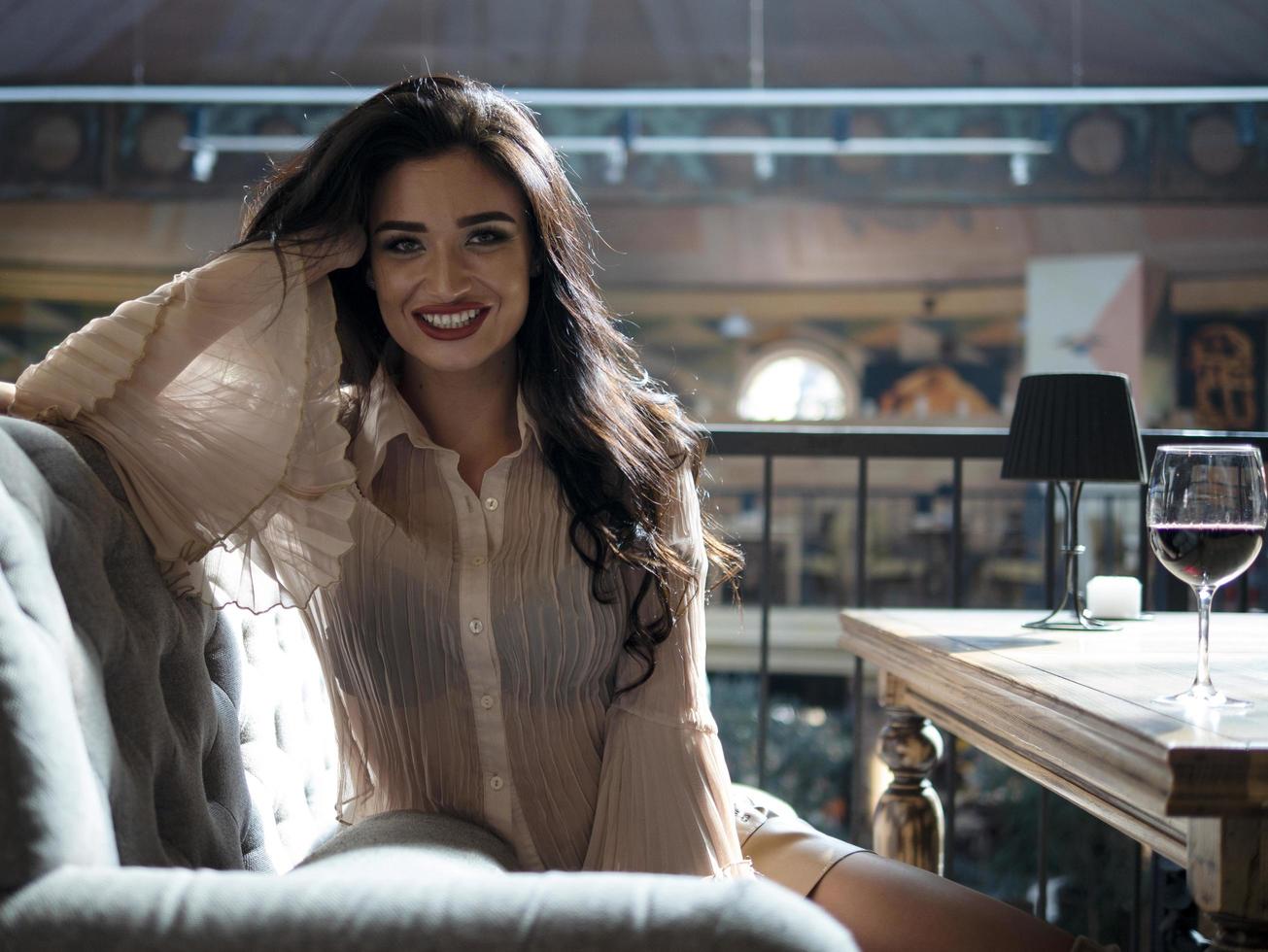 beautiful girl with well-groomed hair laughs looking into the camera while sitting on the couch photo