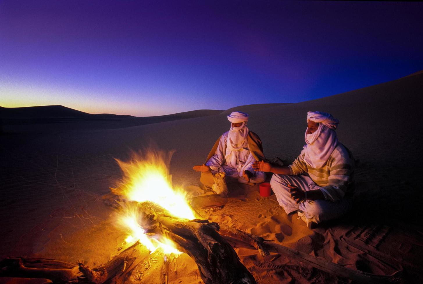 Tikobaouine Italia 2010- personas desconocidas frente al fuego al atardecer en el desierto de Tassili n'ajjer foto