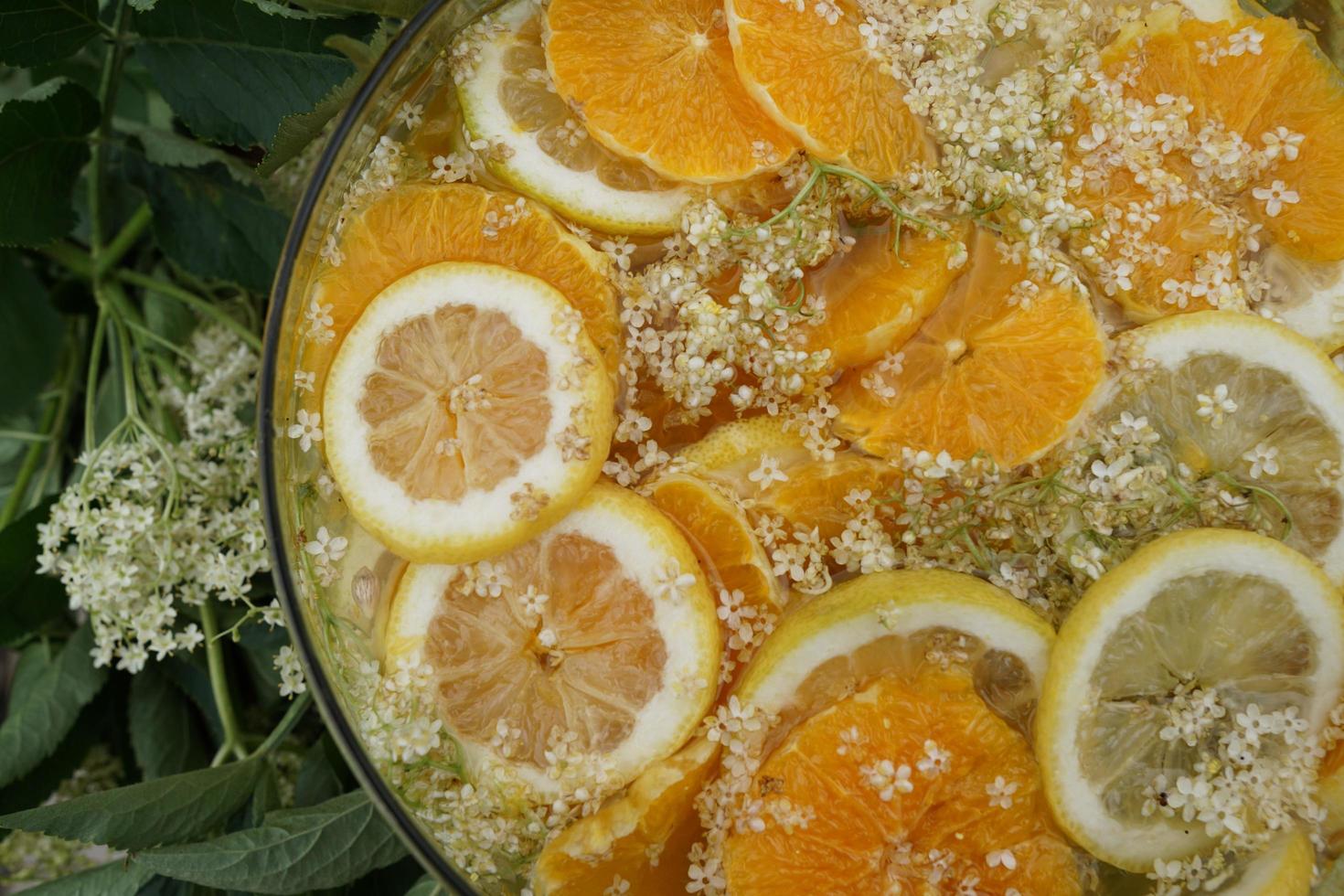 Detalle de rodaja de cítricos y jugo de saúco en el tazón de vidrio. foto