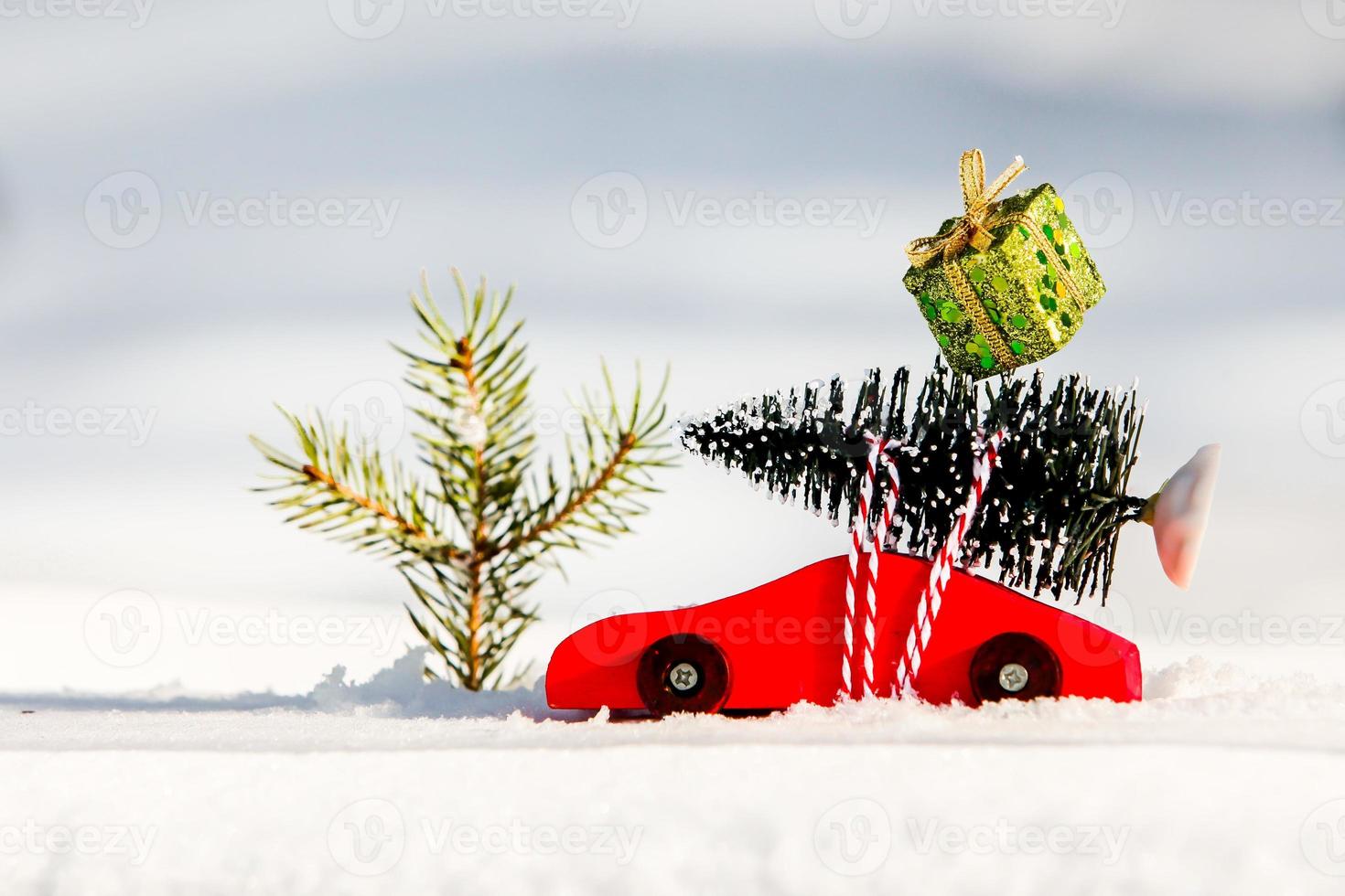 Coche de juguete de madera roja con árbol de navidad y caja de regalo de navidad foto