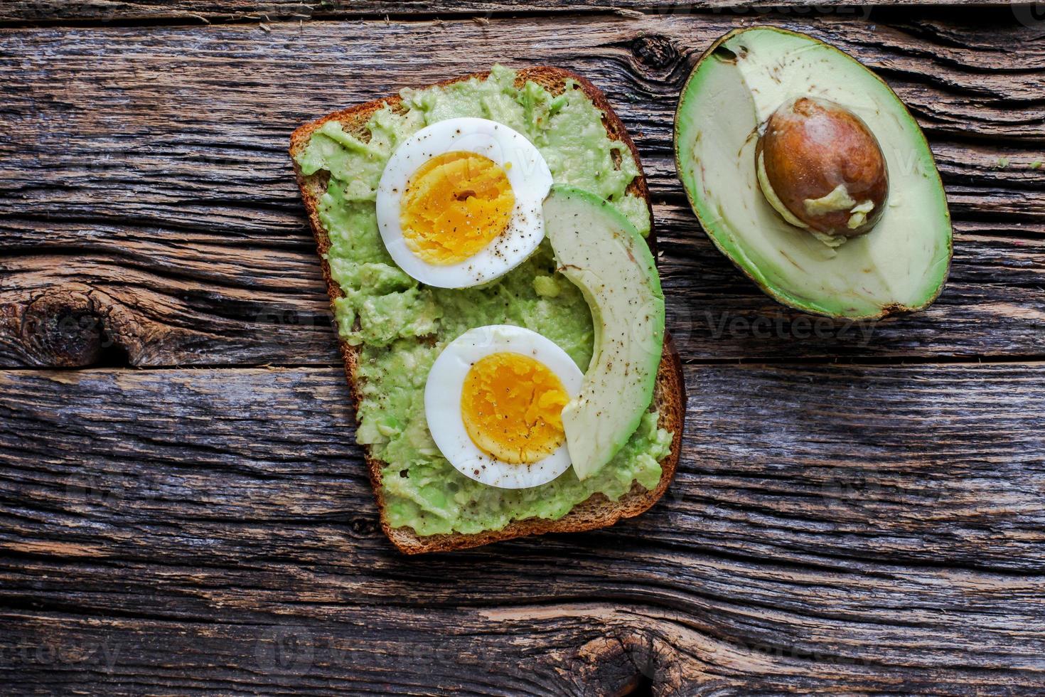 Toast with mashed avocado and eggs on rustic wooden table with photo