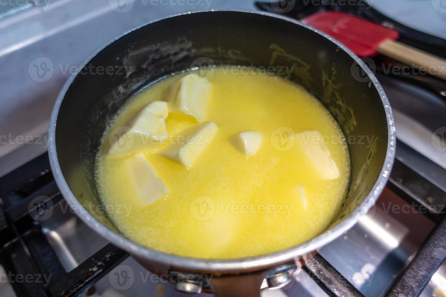 Barra de mantequilla derritiéndose en una olla sobre una estufa de gas foto