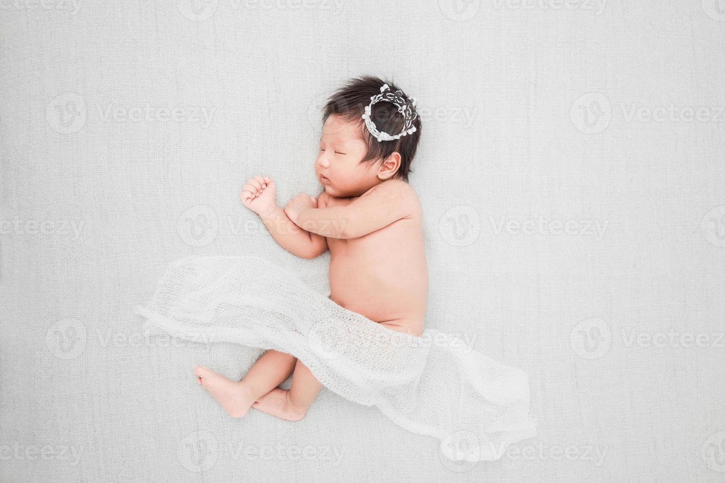 Newborn baby boy sleeping and wearing a silver crown photo