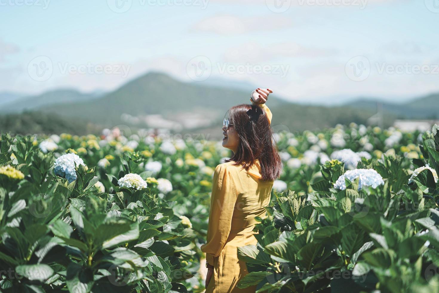 Happy Asian woman holds her hand in a field of Hydrangea flowers photo