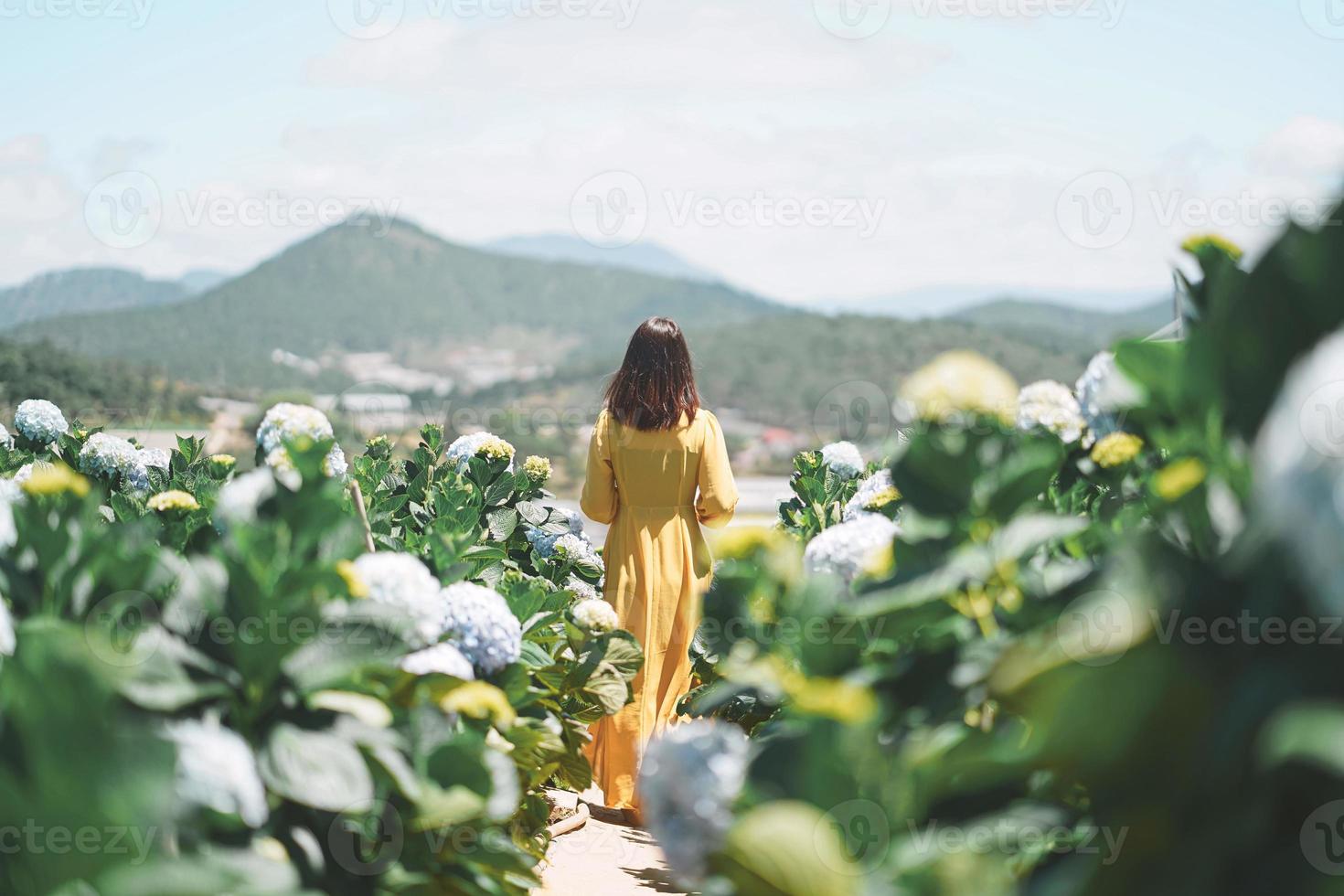 Hermosa mujer asiática en vestido amarillo caminar en el jardín de flores de hortensias foto