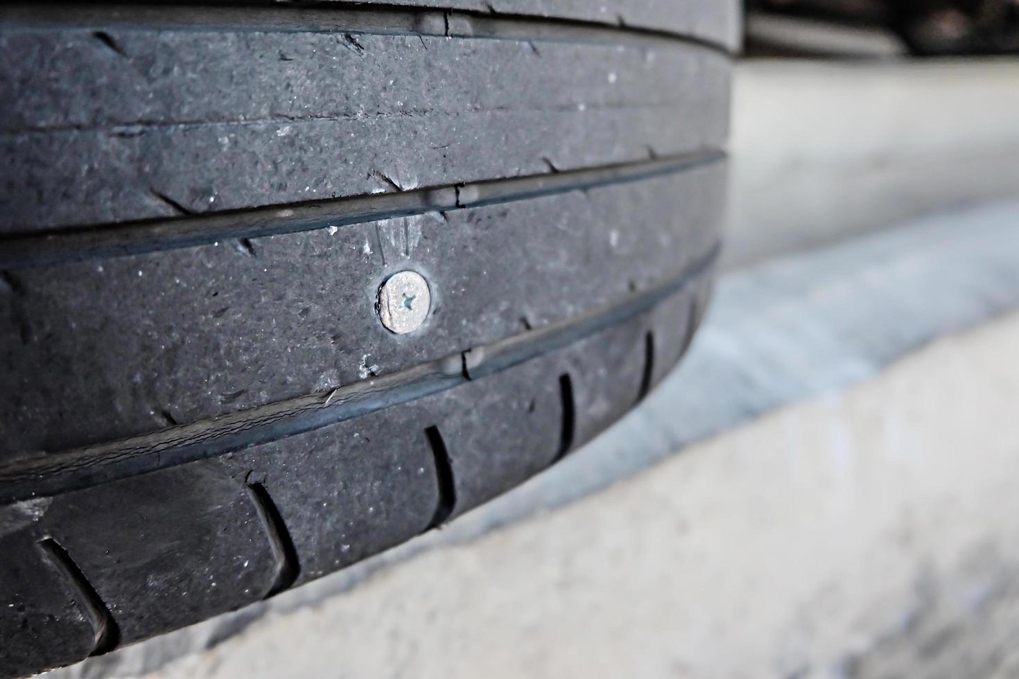 close up of screw nail puncturing car tire photo