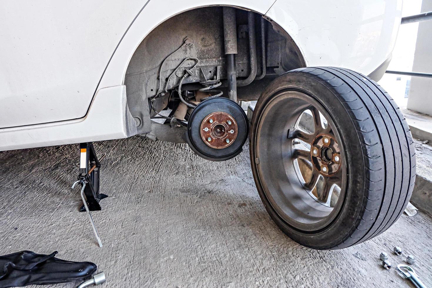 Car mechanic changing tire, changing tire with wheel wrench. photo