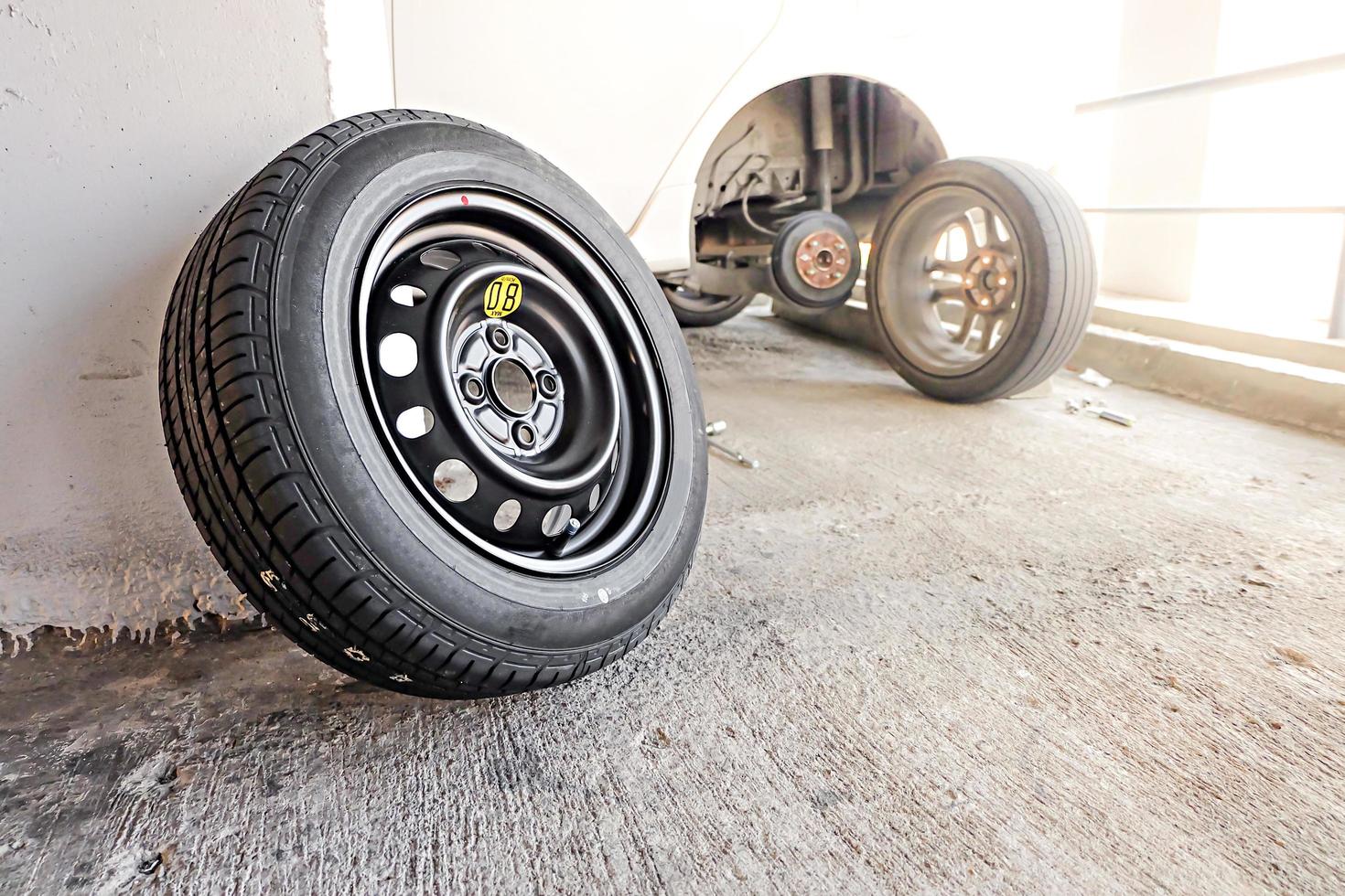 Car mechanic changing tire, changing tire with wheel wrench. photo