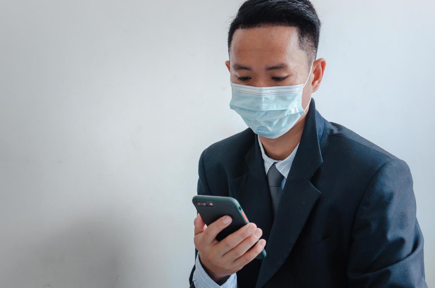 Business men wear face masks to watch mobile phone photo