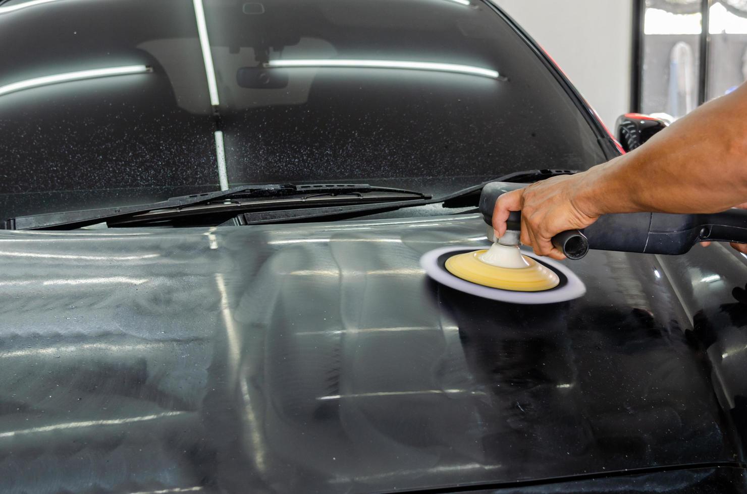 Car detailing - Man working on polishing and caring the exterior with wax. Auto polishing with machine photo