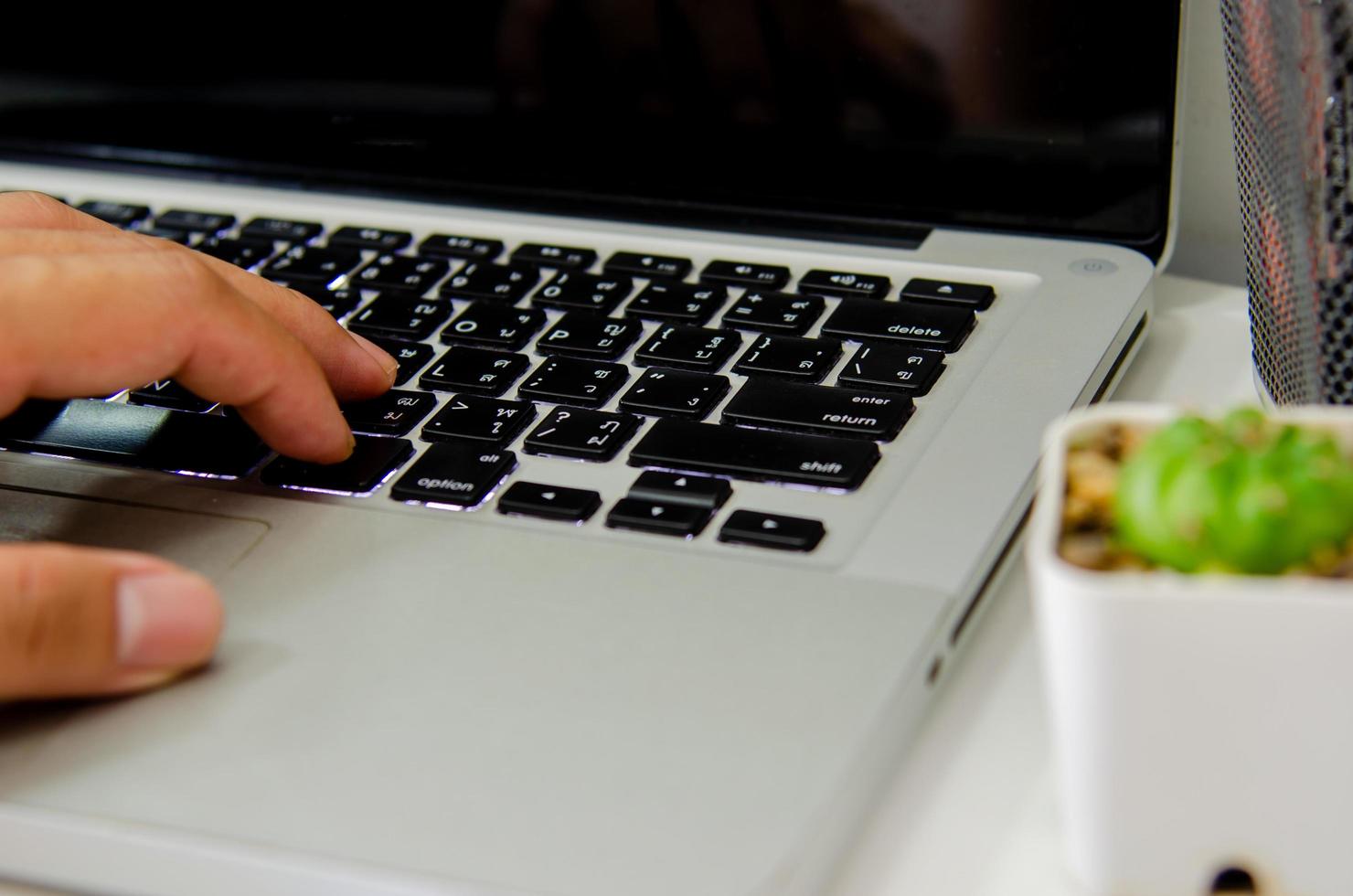 Close up hand typing a keyboard computer laptop on desk photo