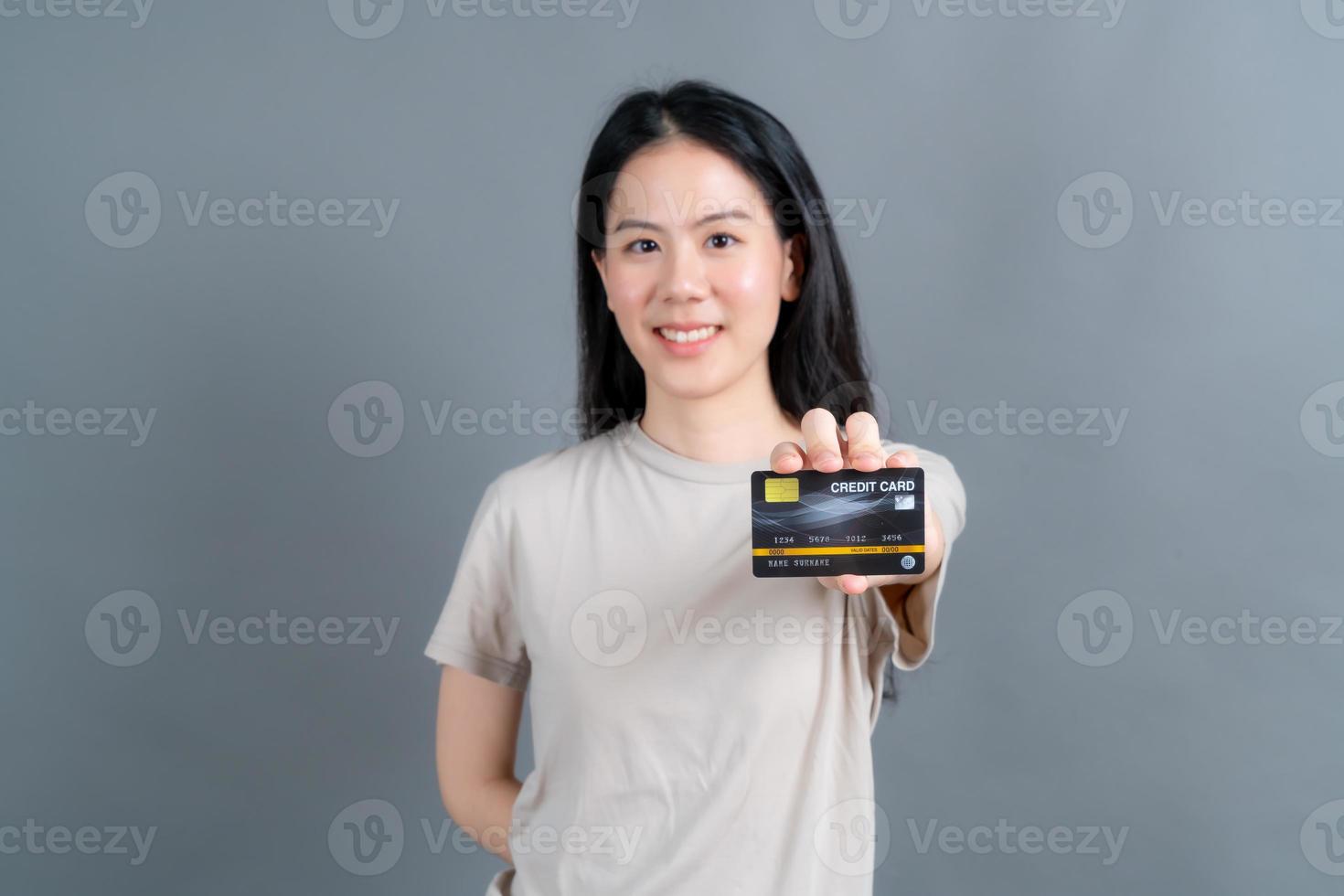 Portrait of a lovely young Asian woman showing credit card photo