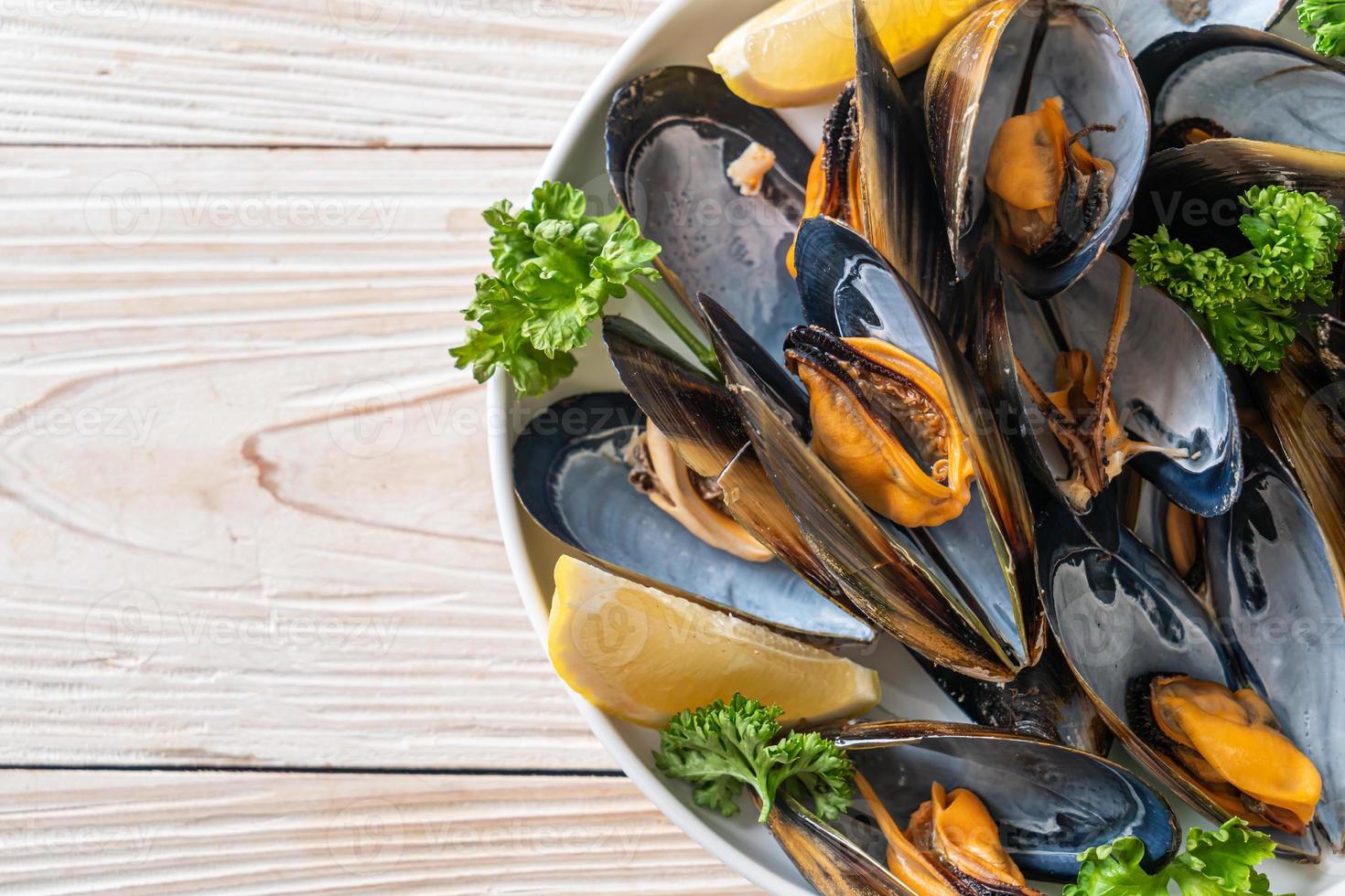 mejillones con hierbas en un bol con limón foto