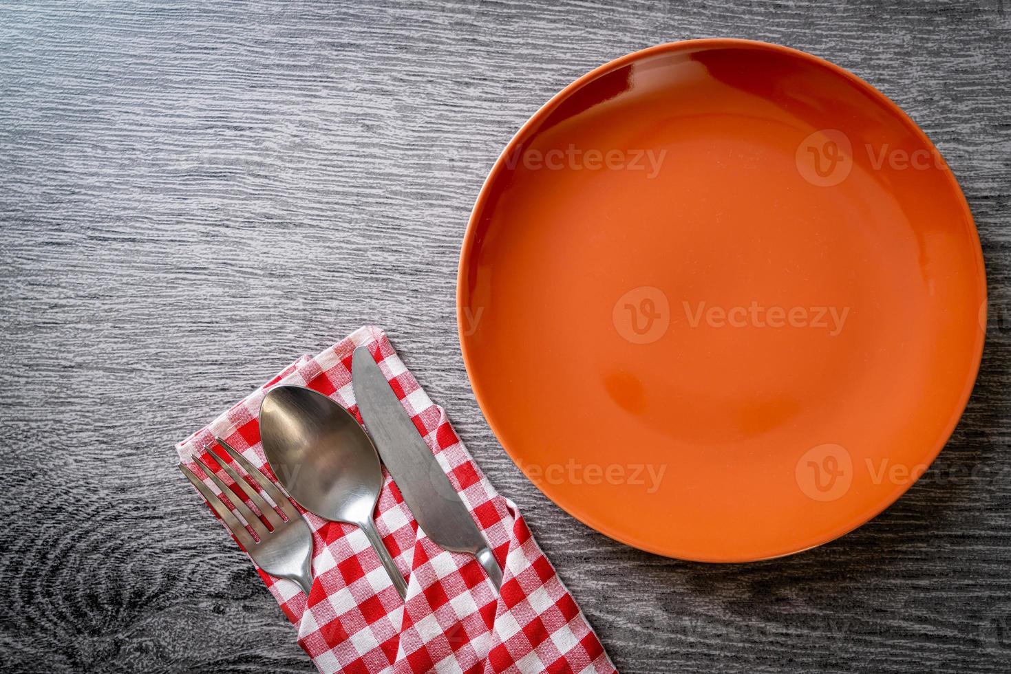 Empty plate or dish with knife, fork, and spoon on wood tile background photo