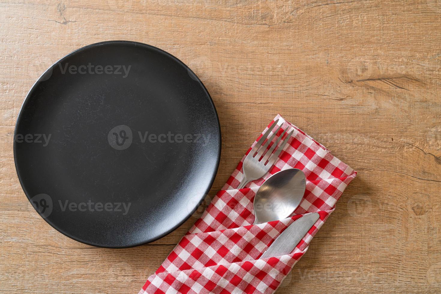 Empty plate or dish with knife, fork, and spoon on wood tile background photo