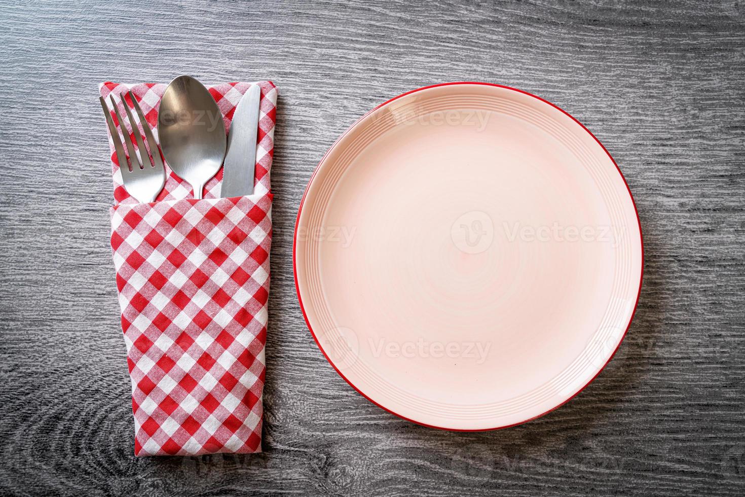 Empty plate or dish with knife, fork, and spoon on wood tile background photo